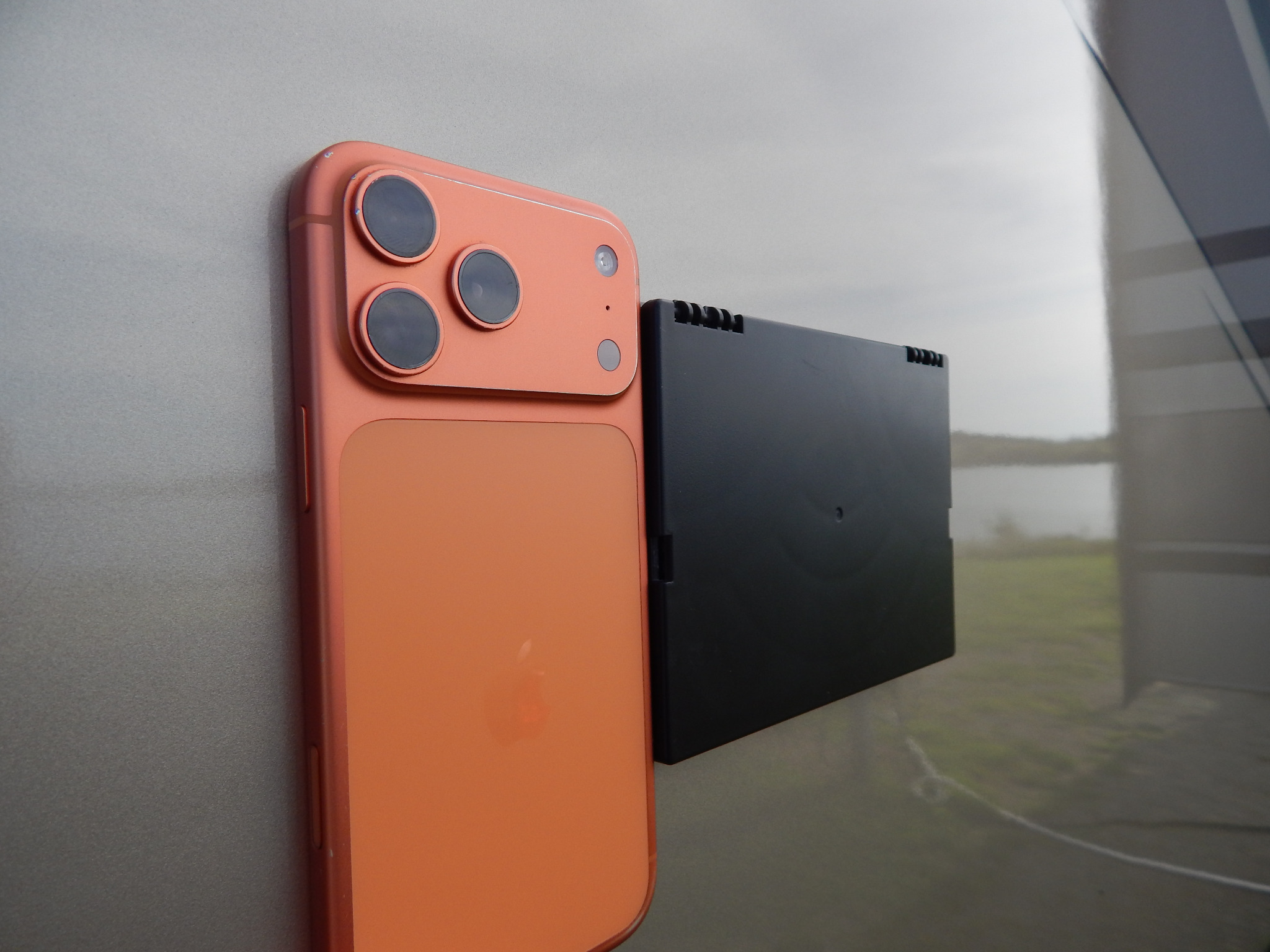 A smartphone held beside the closed Pocket Shelf to demonstrate its slim folded profile